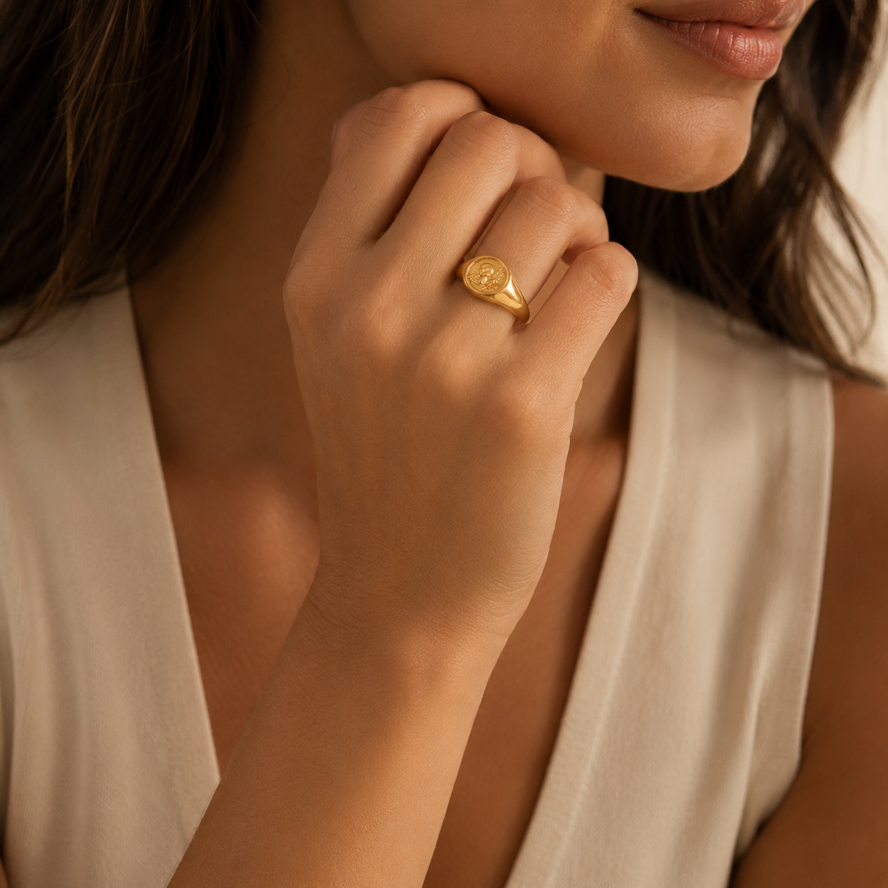Gold signet ring with engraved design on woman's hand, elegant jewelry accessory